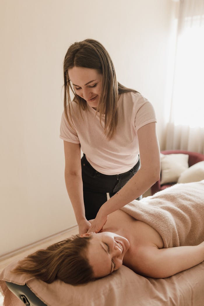 A masseuse provides a soothing massage to a relaxed, smiling client in a serene spa setting.